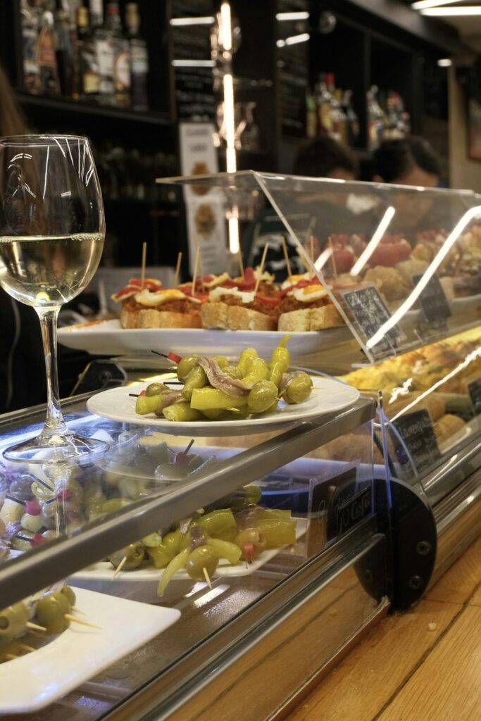Copa de vino blanco con tapas y entrantes para compartir